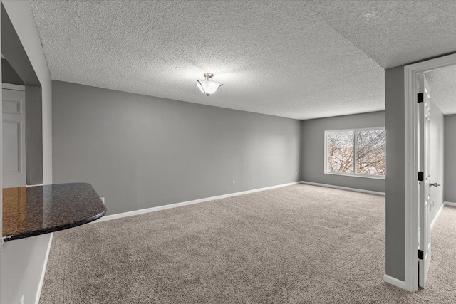 basement with carpet, a textured ceiling, and baseboards