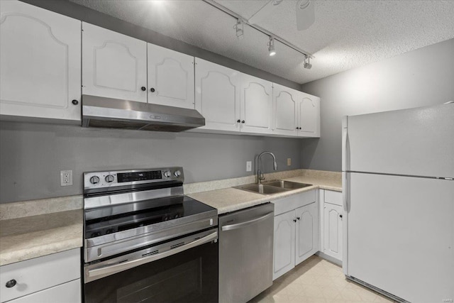 kitchen featuring appliances with stainless steel finishes, a sink, under cabinet range hood, white cabinetry, and a textured ceiling