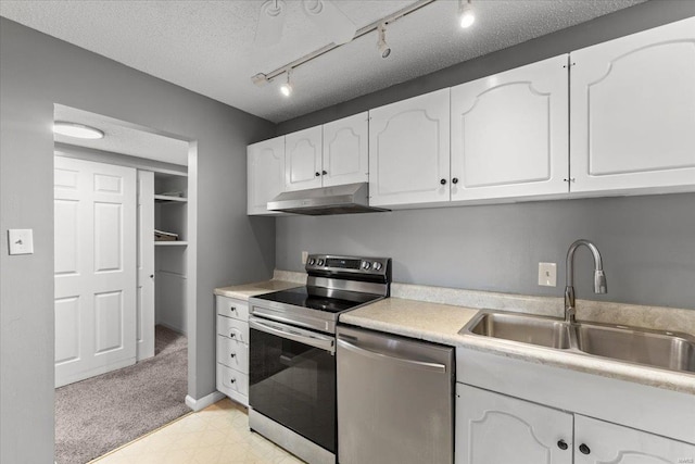 kitchen featuring appliances with stainless steel finishes, under cabinet range hood, a sink, white cabinetry, and a textured ceiling