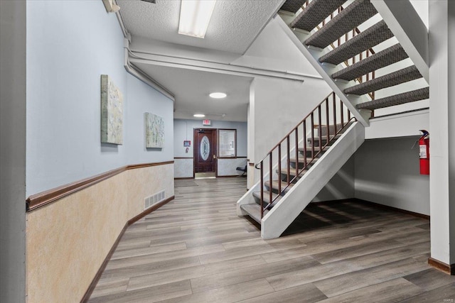 staircase featuring wood finished floors and baseboards