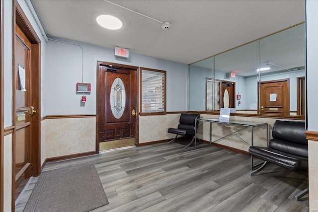 entryway featuring wood finished floors, baseboards, and wainscoting