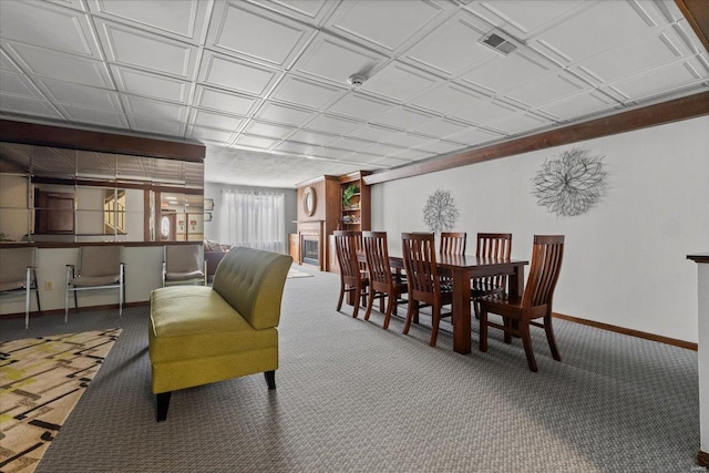 carpeted dining area with baseboards and an ornate ceiling