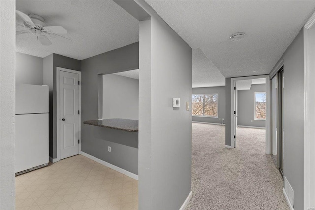 corridor featuring a textured ceiling and baseboards