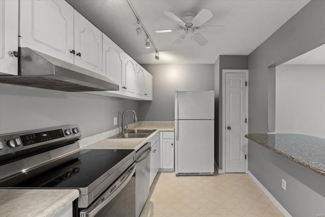 kitchen with appliances with stainless steel finishes, under cabinet range hood, a sink, a textured ceiling, and white cabinetry