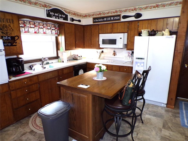 508 N Galloway Rd, Vandalia, MO 63382 - kitchen featuring white appliances, a kitchen island, a sink, brown cabinetry, and a kitchen bar