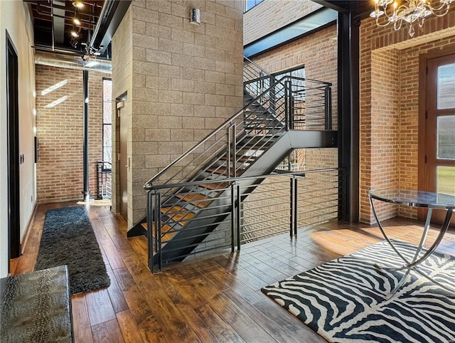 6 E Front St Unit 6, Washington, MO 63090 - staircase featuring brick wall, wood-type flooring, a chandelier, and a high ceiling