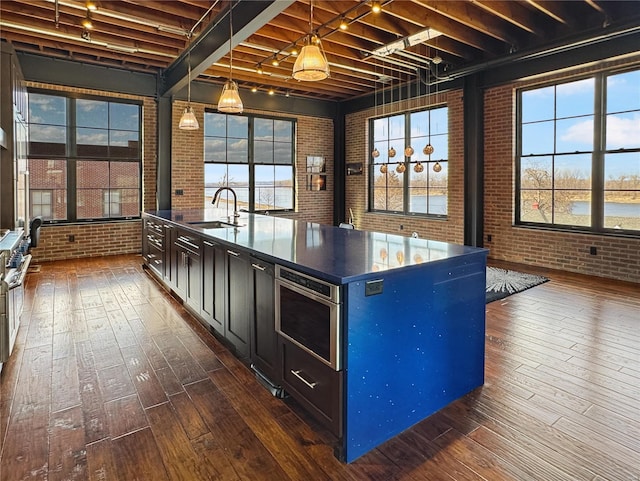 6 E Front St Unit 6, Washington, MO 63090 - kitchen featuring brick wall, a sink, dark wood-style floors, dark countertops, and healthy amount of natural light