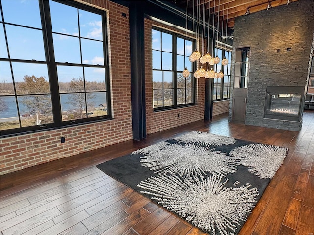 6 E Front St Unit 6, Washington, MO 63090 - unfurnished living room featuring hardwood / wood-style flooring, a stone fireplace, a chandelier, brick wall, and a water view
