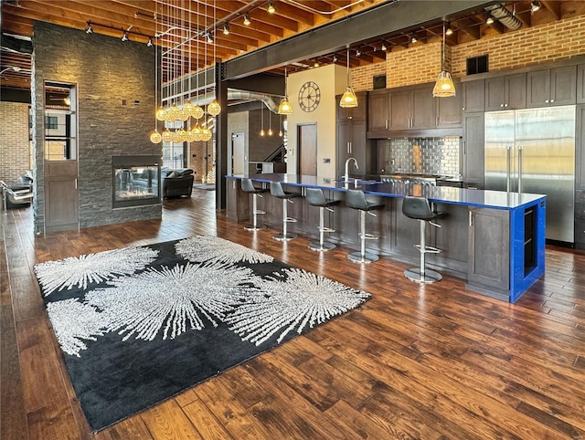 6 E Front St Unit 6, Washington, MO 63090 - kitchen with track lighting, built in fridge, dark countertops, brick wall, and dark wood finished floors