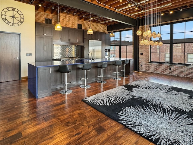 6 E Front St Unit 6, Washington, MO 63090 - kitchen featuring track lighting, brick wall, a sink, dark wood finished floors, and a kitchen breakfast bar