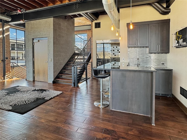 6 E Front St Unit 6, Washington, MO 63090 - kitchen featuring dark wood-type flooring, a kitchen breakfast bar, tasteful backsplash, decorative light fixtures, and a towering ceiling