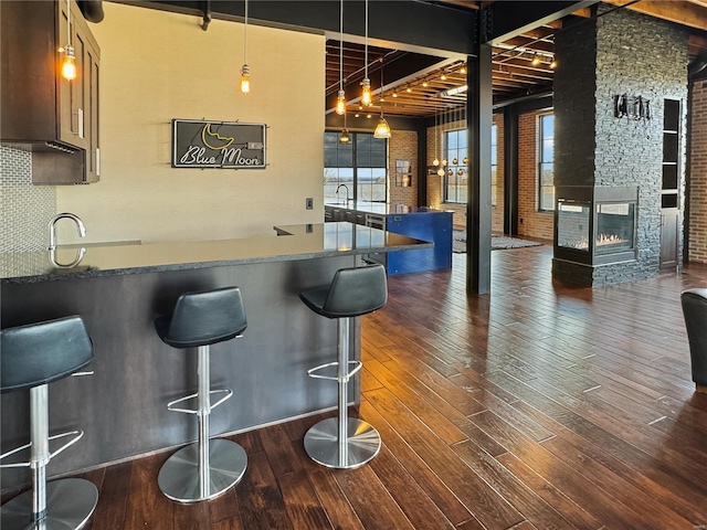 6 E Front St Unit 6, Washington, MO 63090 - bar area featuring dark wood-style floors, decorative backsplash, brick wall, a fireplace, and decorative light fixtures