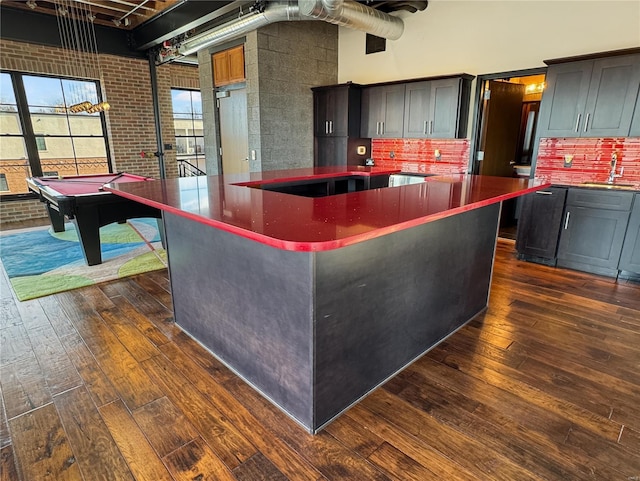 6 E Front St Unit 6, Washington, MO 63090 - kitchen featuring dark countertops, dark wood-style flooring, a sink, a center island, and brick wall