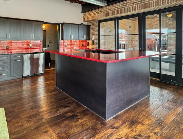 6 E Front St Unit 6, Washington, MO 63090 - kitchen with dark wood finished floors, dark countertops, brick wall, a high ceiling, and backsplash
