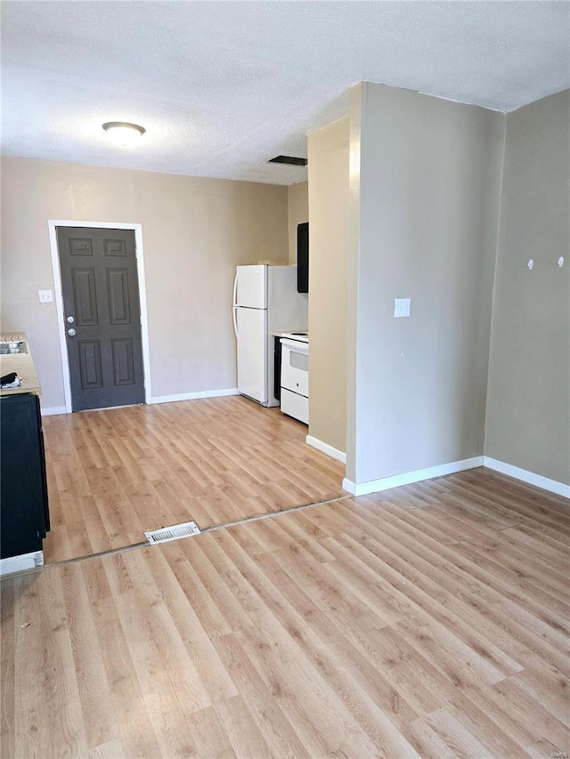 5226 Saint Louis Ave, Saint Louis, MO 63115 - unfurnished living room featuring light wood finished floors, baseboards, and a textured ceiling