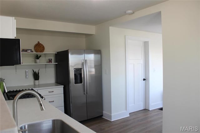 kitchen with stainless steel refrigerator with ice dispenser, white cabinets, light countertops, wood finished floors, and baseboards