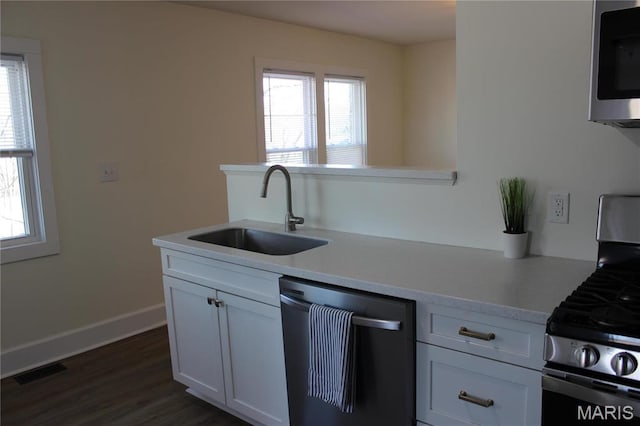 kitchen featuring stainless steel appliances, a sink, light countertops, dark wood-type flooring, and white cabinetry