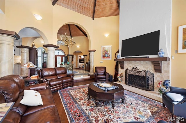 651 Kiefer Creek Rd, Ballwin, MO 63021 - living room featuring decorative columns, high vaulted ceiling, arched walkways, a stone fireplace, and wood finished floors