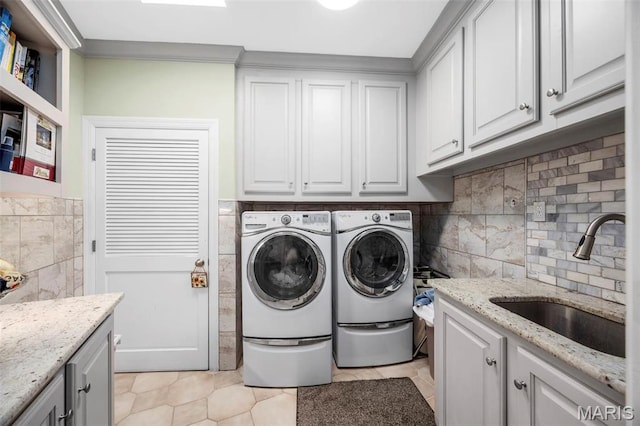 651 Kiefer Creek Rd, Ballwin, MO 63021 - clothes washing area featuring cabinet space, washer and clothes dryer, tile walls, and light tile patterned floors