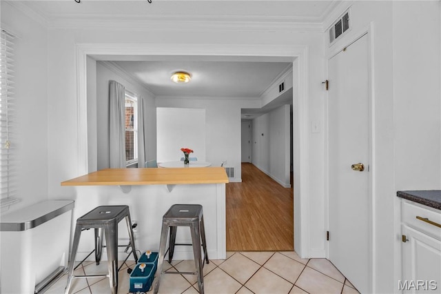 13419 Land O Woods Dr Unit 6, Saint Louis, MO 63141 - kitchen with a kitchen breakfast bar, crown molding, light tile patterned floors, white cabinets, and baseboards