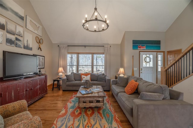 living room with high vaulted ceiling, a chandelier, wood finished floors, and stairs