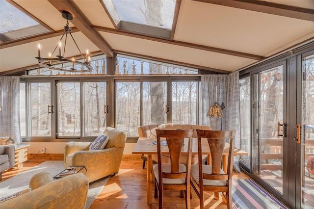 sunroom / solarium with wood-type flooring, plenty of natural light, and a chandelier