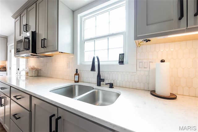 11720 County Road 5160, Rolla, MO 65401 - kitchen featuring a sink, stainless steel microwave, gray cabinetry, tasteful backsplash, and light stone countertops