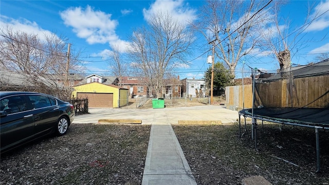 3683 Montana St, Saint Louis, MO 63116 - view of yard featuring a trampoline, fence, an outbuilding, and a detached garage