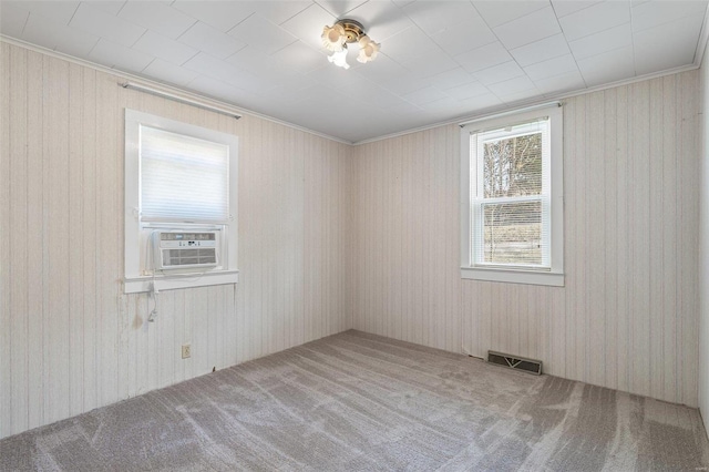 empty room with carpet flooring, crown molding, cooling unit, and wooden walls