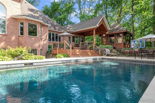outdoor pool with a gazebo, a wooden deck, a ceiling fan, and stairs