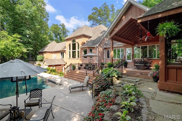 view of patio with a wooden deck, ceiling fan, an outdoor pool, and outdoor dining area