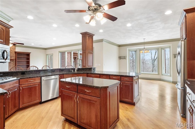 kitchen with appliances with stainless steel finishes, a sink, light wood finished floors, a ceiling fan, and ornamental molding