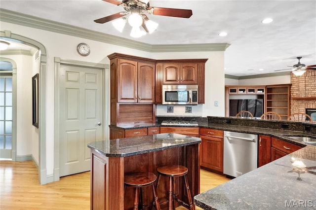 kitchen with stainless steel appliances, ceiling fan, a sink, light wood-style flooring, and crown molding