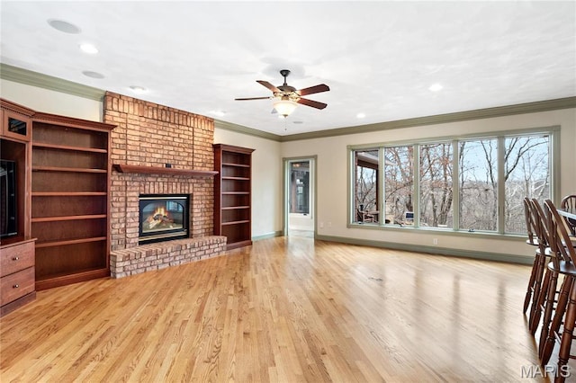 unfurnished living room featuring crown molding, a ceiling fan, wood finished floors, a fireplace, and baseboards