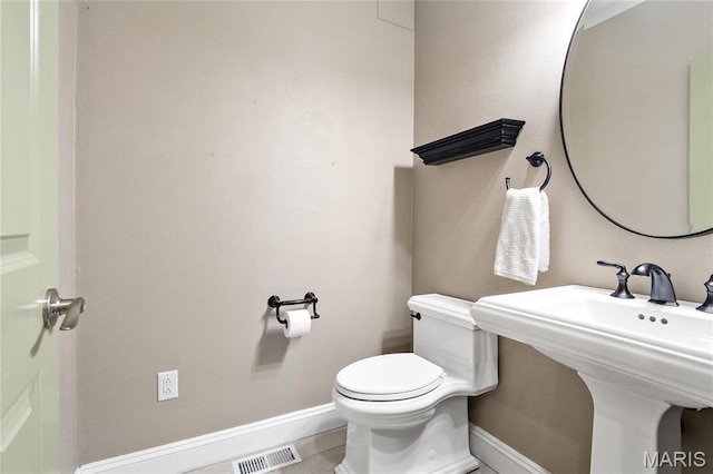 half bath with toilet, baseboards, and a sink