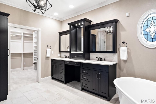 bathroom with double vanity, a freestanding tub, a chandelier, crown molding, and a spacious closet