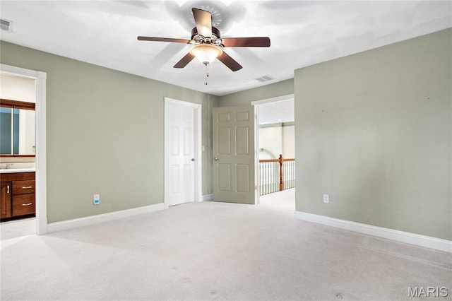 unfurnished bedroom featuring baseboards, light carpet, ensuite bath, and a ceiling fan