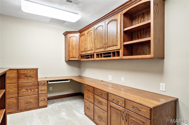 unfurnished office with light colored carpet, built in desk, and baseboards