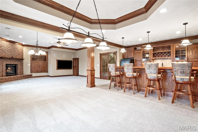 kitchen featuring freestanding refrigerator, ornamental molding, a fireplace, light colored carpet, and hanging light fixtures