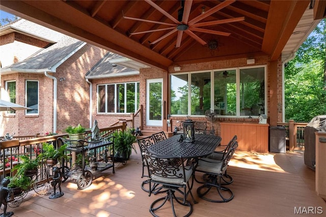 wooden terrace featuring outdoor dining area and a ceiling fan