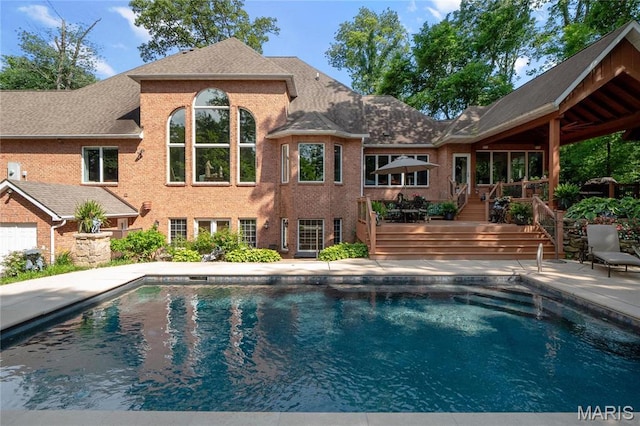 outdoor pool with stairway, a deck, and a patio area