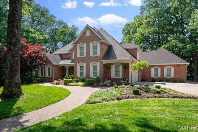 view of front of property featuring driveway, a garage, brick siding, and a front yard