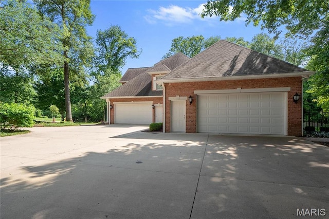 view of front of property featuring concrete driveway, brick siding, an attached garage, and roof with shingles