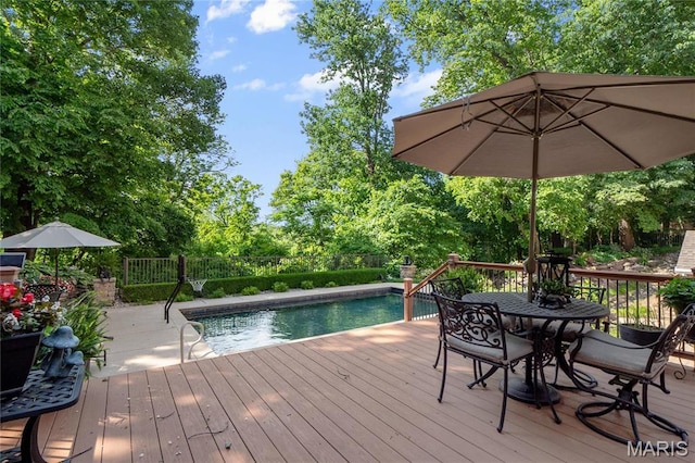 wooden terrace with outdoor dining space, fence, and view of scattered trees
