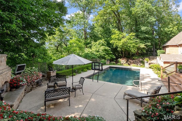 view of swimming pool with a patio, a fenced backyard, and view of scattered trees