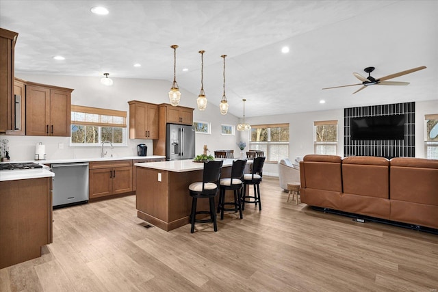 kitchen with stainless steel appliances, vaulted ceiling, open floor plan, a sink, and a kitchen breakfast bar