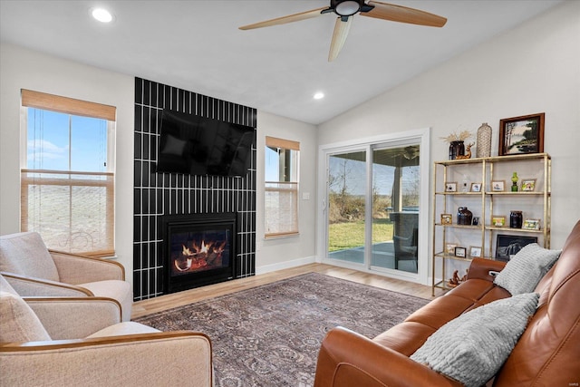 living room featuring recessed lighting, plenty of natural light, vaulted ceiling, a large fireplace, and wood finished floors