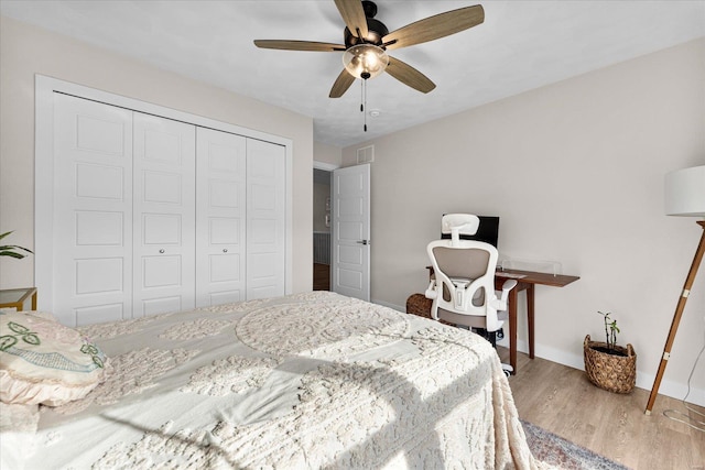 bedroom with a closet, wood finished floors, baseboards, and a ceiling fan