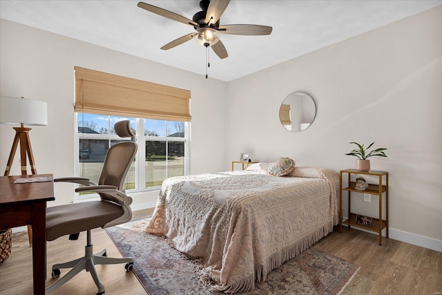 bedroom with wood finished floors, baseboards, ceiling fan, and a desk