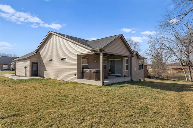 back of house with a hot tub, a patio, and a lawn